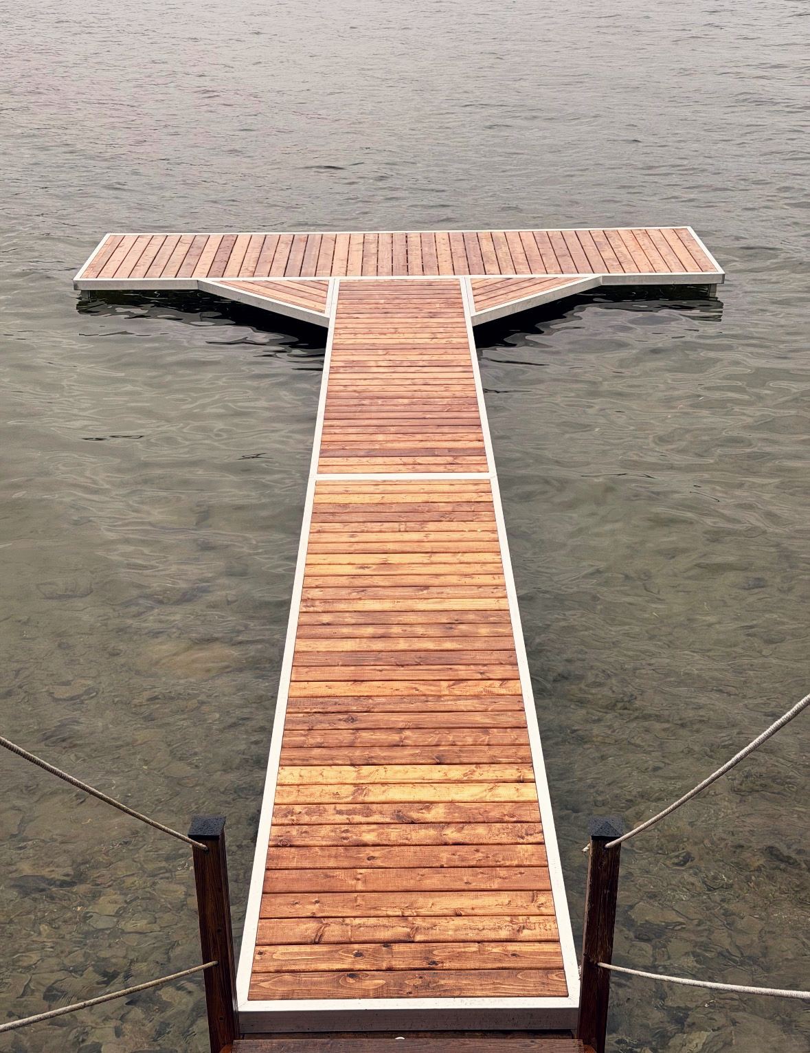 Aluminum-framed cedar pole dock with a T-head, posts standing on the lake bottom