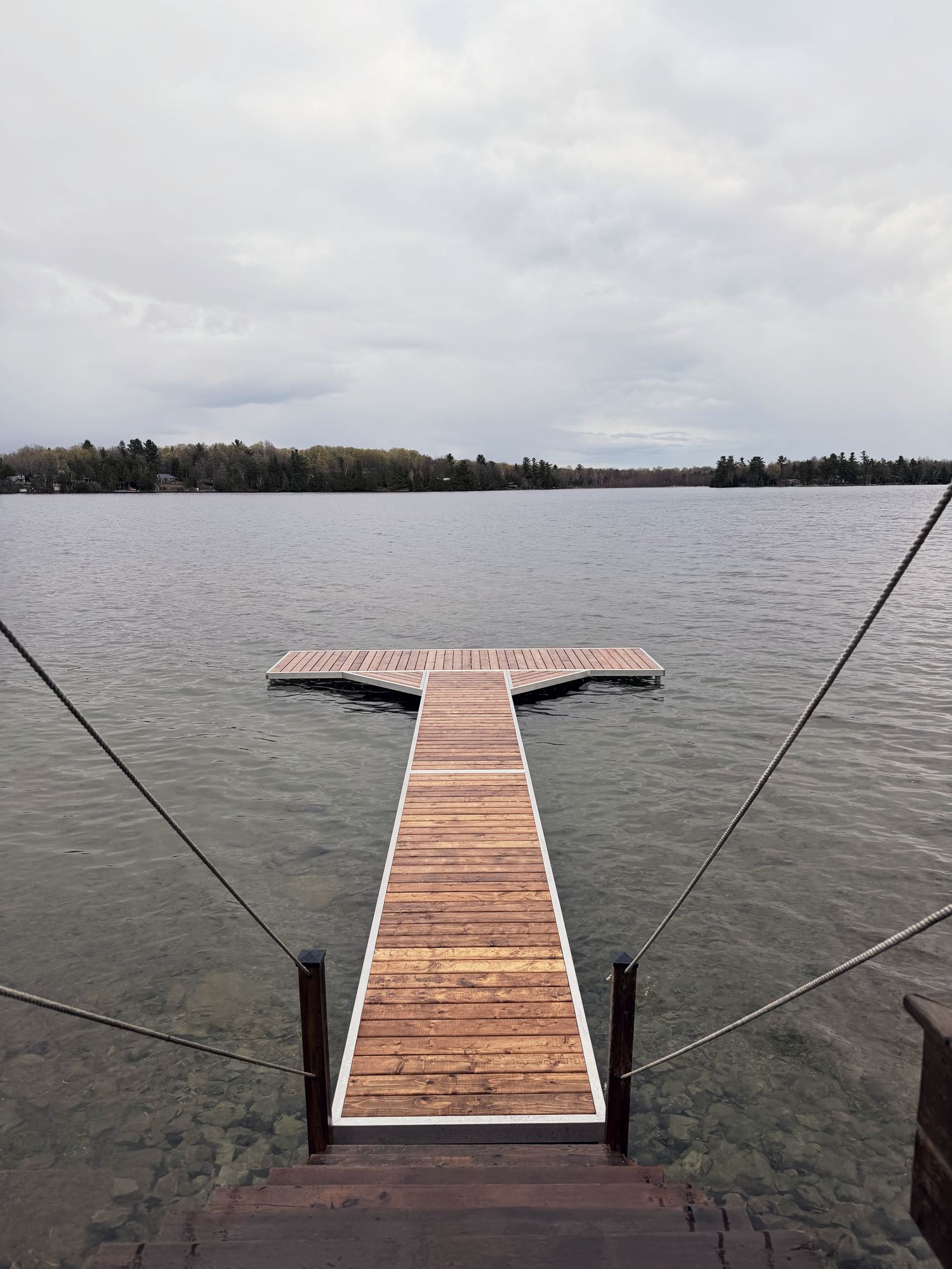 Aluminum-framed cedar pole dock with a T-head, on clear shallow water